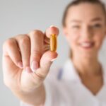 Wanita memegang pil suplemen vitamin