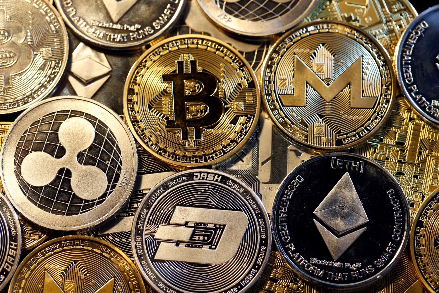 A pile of gold coins with different cryptocurrency symbols on them.