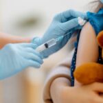 Anak kecil yang memegang boneka boneka vaksin boneka