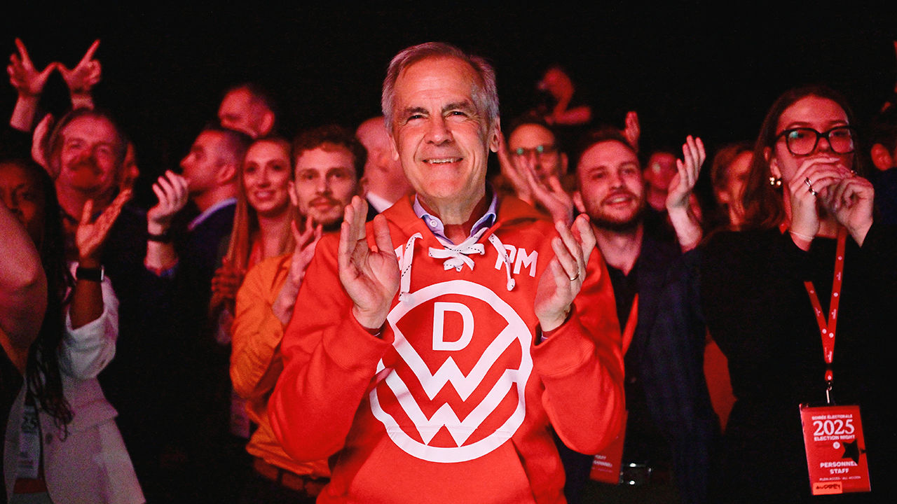 Canada's Prime Minister Mark Carney applauds as he stands next to supporters during an event at the Liberal Party election night headquarters.